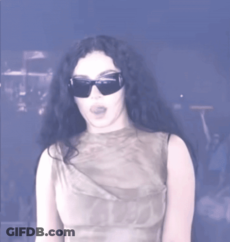 A Woman Wearing Sunglasses And A Sleeveless Top GIF