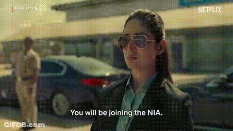 A Woman Wearing Sunglasses And A Suit Is Talking To A Man In A Car . GIF