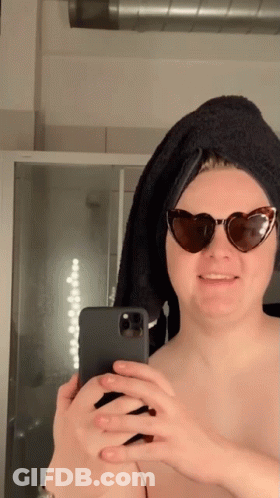 A Woman Wearing Sunglasses And A Towel On Her Head Takes A Selfie With Her Phone GIF