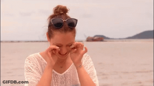 A Woman Wearing Sunglasses And A White Lace Shirt Looks Down GIF