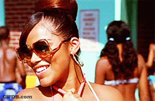 A Woman Wearing Sunglasses And Earrings Is Smiling GIF