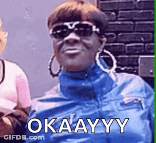 A Woman Wearing Sunglasses And Hoop Earrings Is Making A Funny Face And Saying Okay . GIF