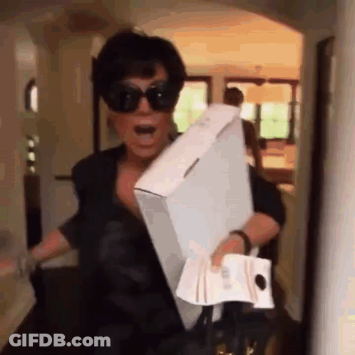 A Woman Wearing Sunglasses Is Carrying A Large Box And A Bag . GIF