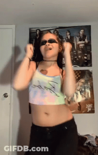 A Woman Wearing Sunglasses Is Dancing In Front Of A Poster Of A Band Called A-Ha GIF