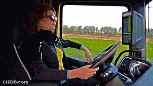 A Woman Wearing Sunglasses Is Driving A Truck With A Steering Wheel That Says Volvo On It GIF