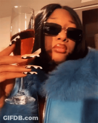 A Woman Wearing Sunglasses Is Holding A Wine Glass GIF