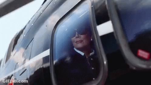A Woman Wearing Sunglasses Is Looking Out Of A Helicopter Window . GIF