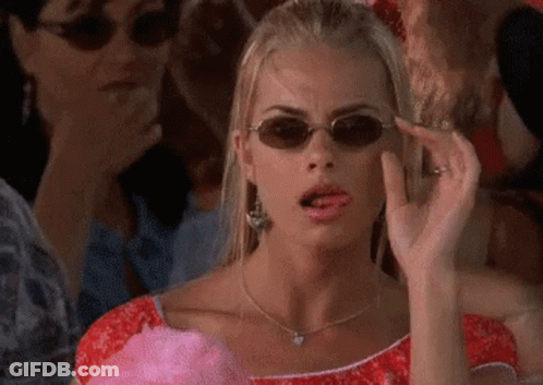 A Woman Wearing Sunglasses Is Making A Funny Face While Holding Cotton Candy . GIF