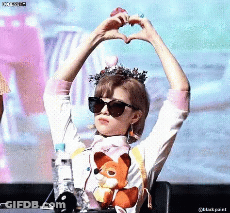 A Woman Wearing Sunglasses Is Making A Heart With Her Hands . GIF