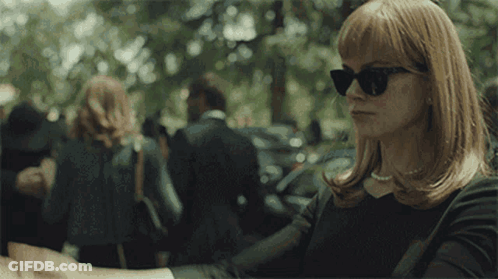 A Woman Wearing Sunglasses Is Shaking Hands With A Man . GIF