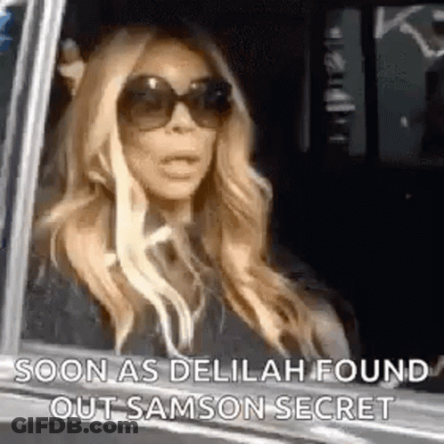 A Woman Wearing Sunglasses Is Sitting In A Car And Looking Out The Window . GIF