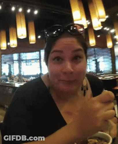 A Woman Wearing Sunglasses Is Sitting In A Restaurant GIF