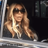 A Woman Wearing Sunglasses Is Sitting In The Back Seat Of A Car . GIF