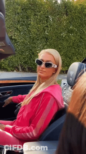 A Woman Wearing Sunglasses Is Sitting In The Back Seat Of A Car . GIF