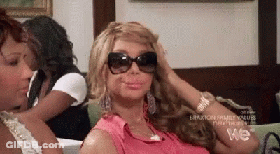 A Woman Wearing Sunglasses Is Sitting On A Couch . GIF