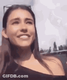 A Woman Wearing Sunglasses Is Smiling And Looking At The Camera While Sitting In A Car . GIF