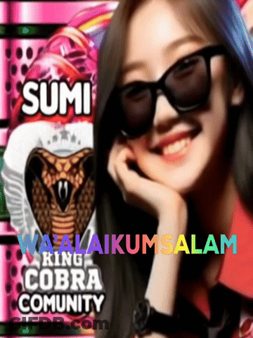 A Woman Wearing Sunglasses Is Smiling In Front Of A Sign That Says Sumi Ring Cobra Community GIF