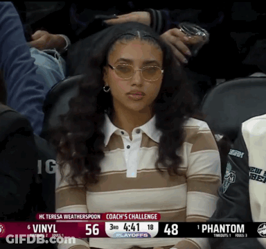 A Woman Wearing Sunglasses Sits In The Stands Watching A Basketball Game GIF