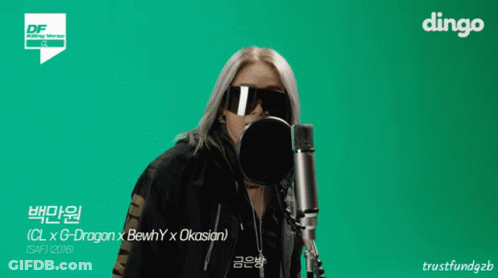A Woman Wearing Sunglasses Stands In Front Of A Microphone With Dingo In The Corner GIF