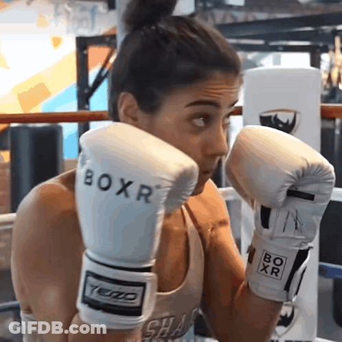 A Woman Wearing White Boxr Boxing Gloves In A Boxing Ring GIF