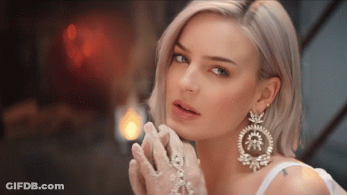 A Woman Wearing White Gloves And Large Earrings GIF