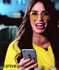 A Woman Wearing Yellow Sunglasses And A Yellow Shirt Is Holding A Cell Phone . GIF