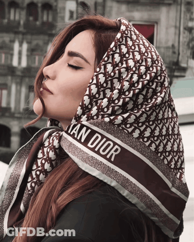A Woman Wears A Scarf That Says Christian Dior On It GIF