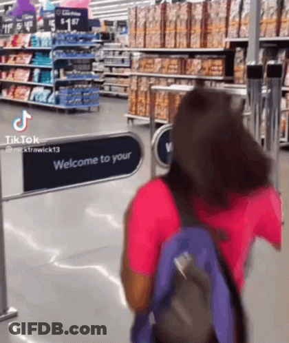 A Woman With A Backpack Is Walking Through A Welcome To Your Sign In A Grocery Store GIF