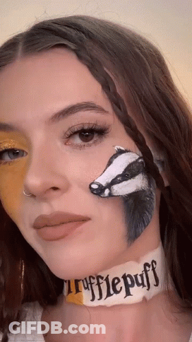 A Woman With A Badger Painted On Her Face And A Choker That Says ' Rufflepuff ' On It GIF