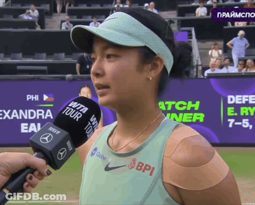 A Woman With A Bandage On Her Arm Is Being Interviewed By A Bpi Microphone GIF