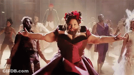 A Woman With A Beard In A Red Dress Is Dancing In Front Of A Group Of People . GIF
