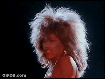 A Woman With A Big Afro Is Wearing A Red Dress And Pearls GIF