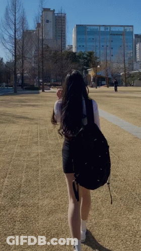 A Woman With A Black Backpack Is Walking In A Field GIF