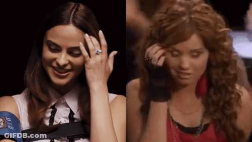 A Woman With A Blue Ring On Her Finger Is Smiling Next To A Woman With Curly Hair GIF