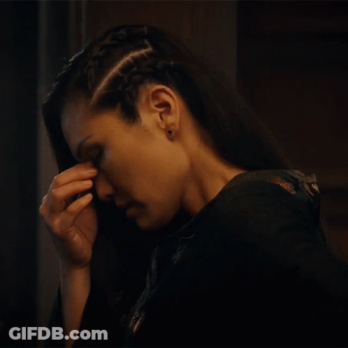 A Woman With A Braid In Her Hair Has Her Hand On Her Forehead GIF