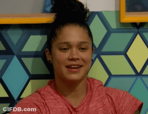 A Woman With A Bun On Her Head Is Smiling In Front Of A Wall With Geometric Shapes GIF