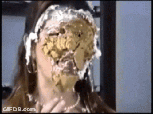 A Woman With A Cake On Her Face Is Sitting In Front Of A Window . GIF
