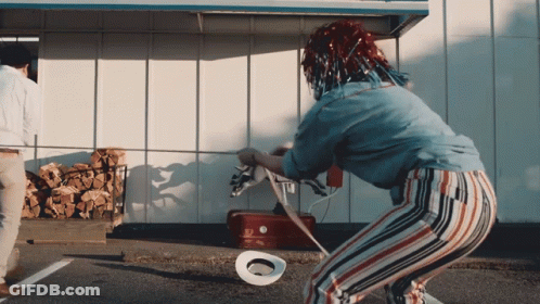 A Woman With A Cowboy Hat On The Ground In Front Of A Red Cooler GIF