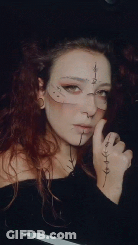 A Woman With A Cross On Her Face Has A Tattoo On Her Hand GIF