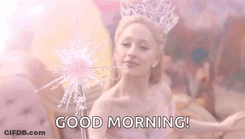 A Woman With A Crown On Her Head Is Holding A Wand And Saying `` Good Morning '' . GIF