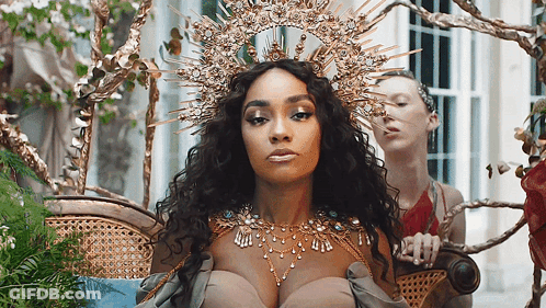 Woman With Crown Sitting In Chair With Another Woman GIF