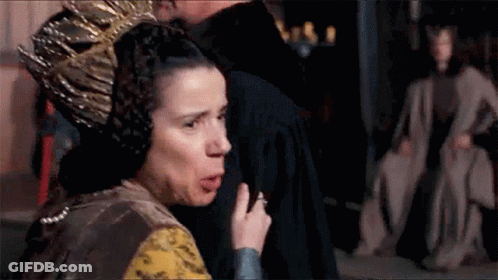 A Woman With A Crown On Her Head Is Standing Next To A Man In A Room . GIF