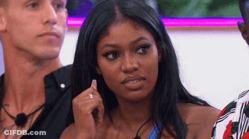 A Woman With A Diamond Ring On Her Finger Is Sitting In Front Of Two Men GIF