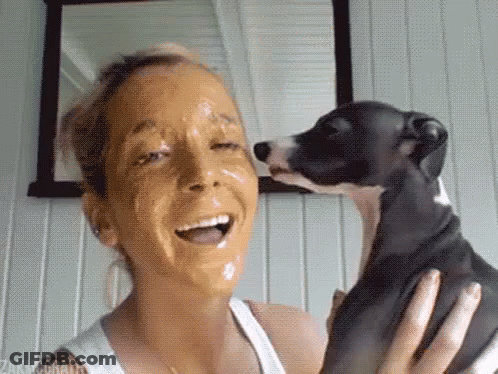 A Woman With A Face Mask On Her Face Is Holding A Dog . GIF