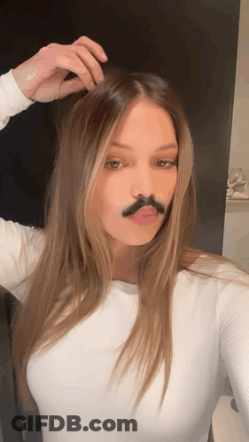 A Woman With A Fake Mustache On Her Face Takes A Selfie GIF