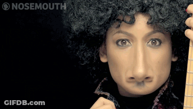 A Woman With A Fake Nose Is Holding A Guitar And Making A Face GIF