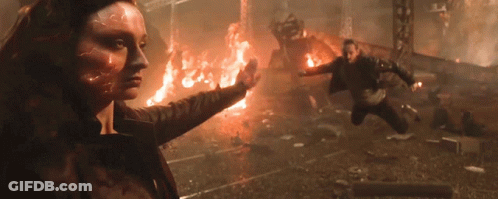 A Woman With A Flame On Her Face Is Standing In Front Of A Burning Building GIF