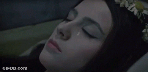 A Woman With A Flower Crown On Her Head Is Laying In Bed With Her Eyes Closed GIF