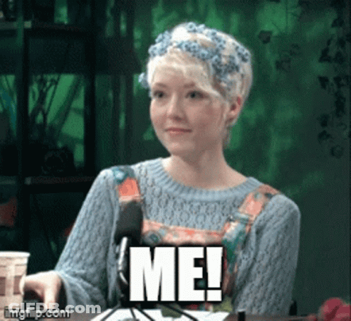 A Woman With A Flower Crown On Her Head Is Sitting In Front Of A Microphone And Says Me GIF