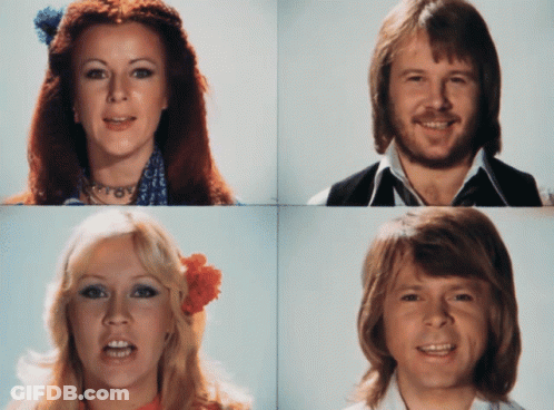 A Woman With A Flower In Her Hair And A Man With A Beard Smile For The Camera GIF